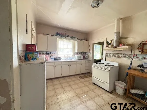 a kitchen with a stove a sink dishwasher and white cabinets with wooden floor