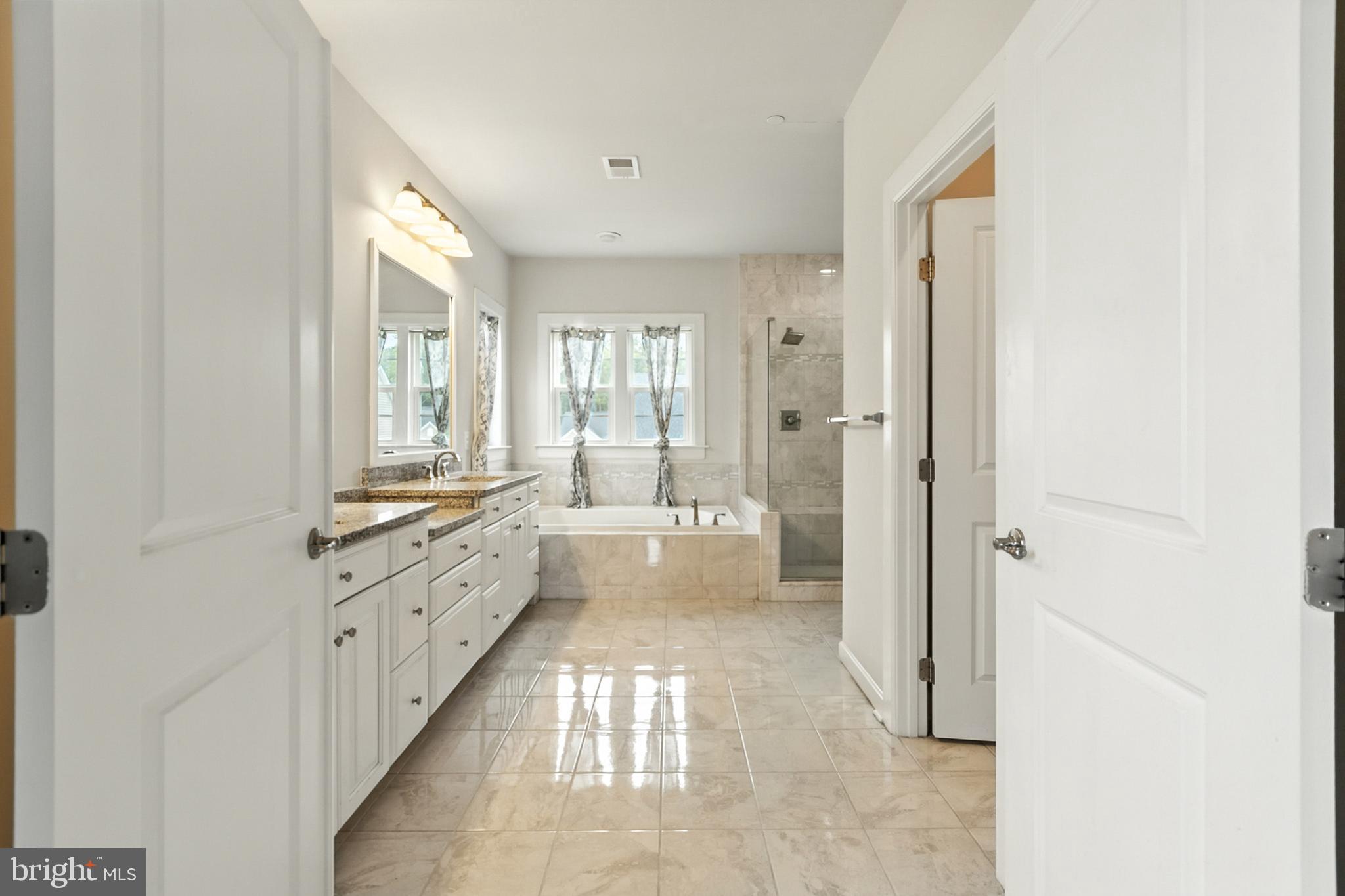4300 Open Field Court Bowie, MD 20720 - Photo 32 of 53 a bathroom with granite countertop a two sinks a large mirror and a bathtub next to a window