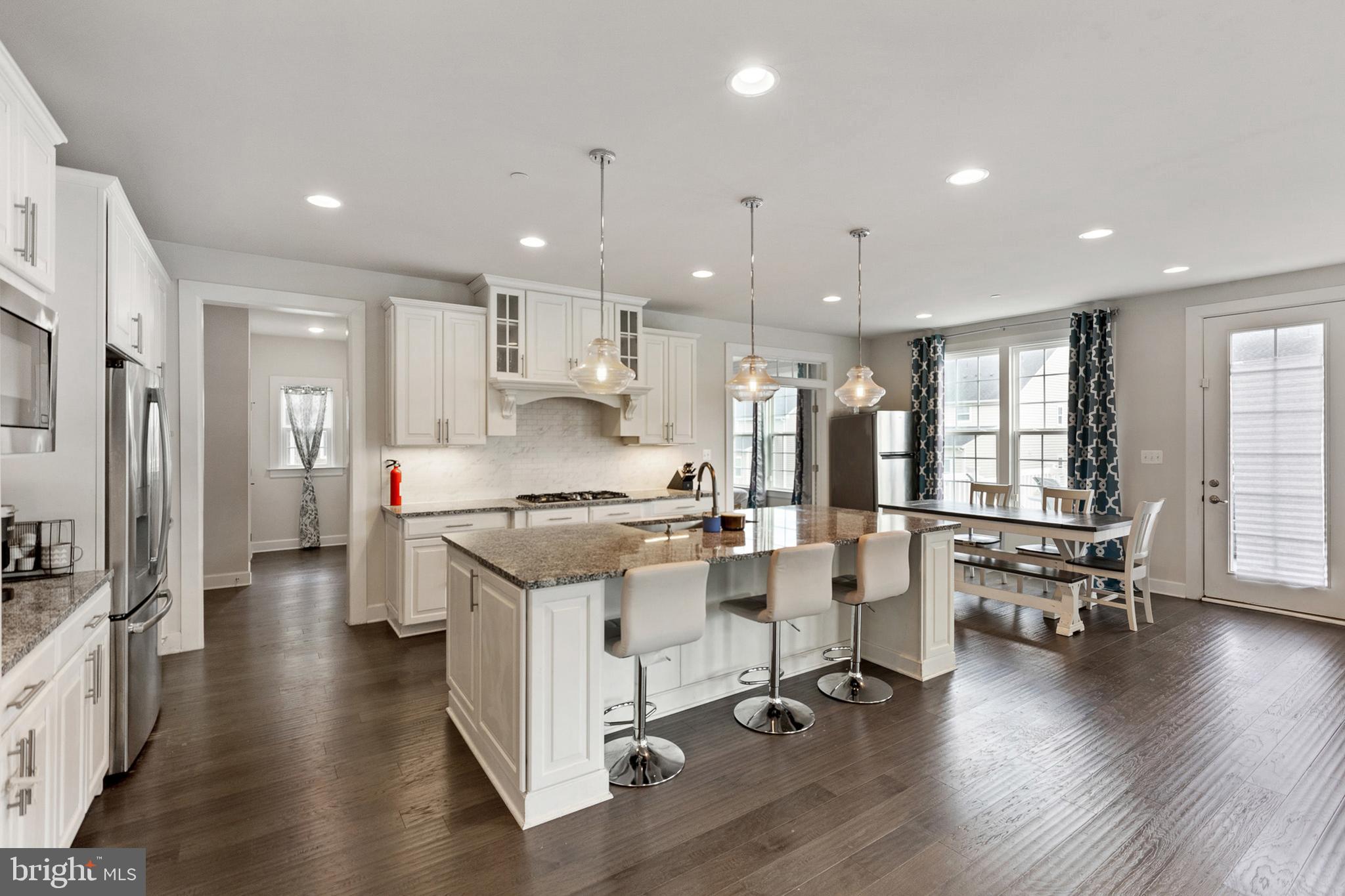 4300 Open Field Court Bowie, MD 20720 - Photo 8 of 53 a kitchen with stainless steel appliances granite countertop a stove top oven a refrigerator a dining table and chairs with wooden floor