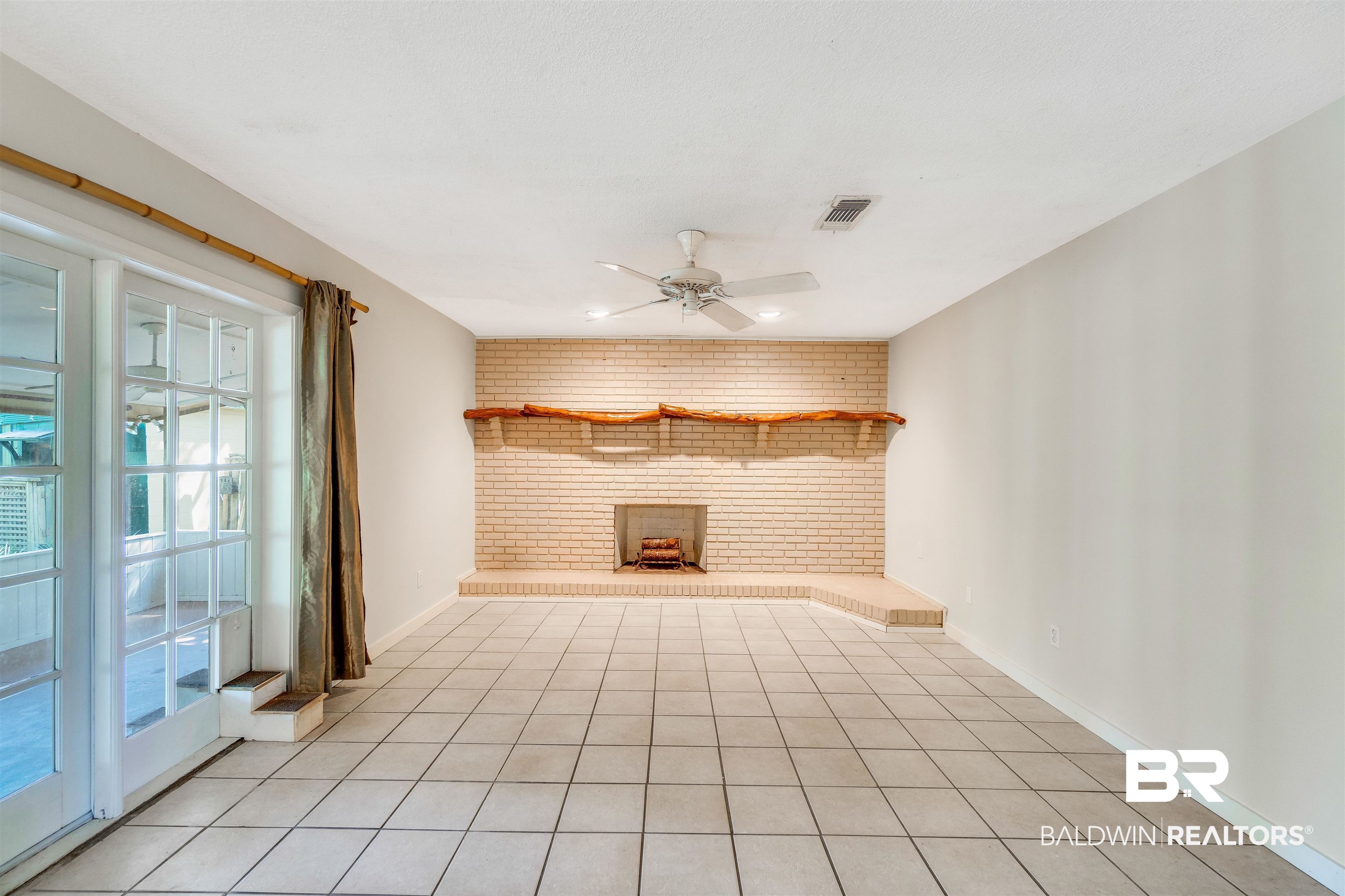 34341 Lost River Road Seminole, AL 36574 - Photo 5 of 36 Unfurnished living room featuring a fireplace, ceiling fan, brick wall, and light tile patterned flooring
