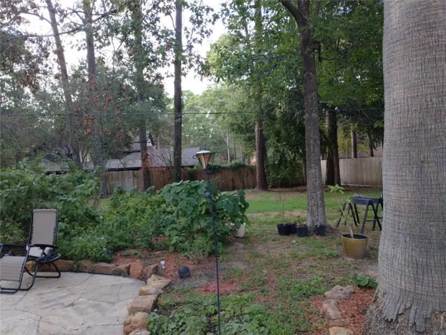a view of a patio with table and chairs plants and large trees