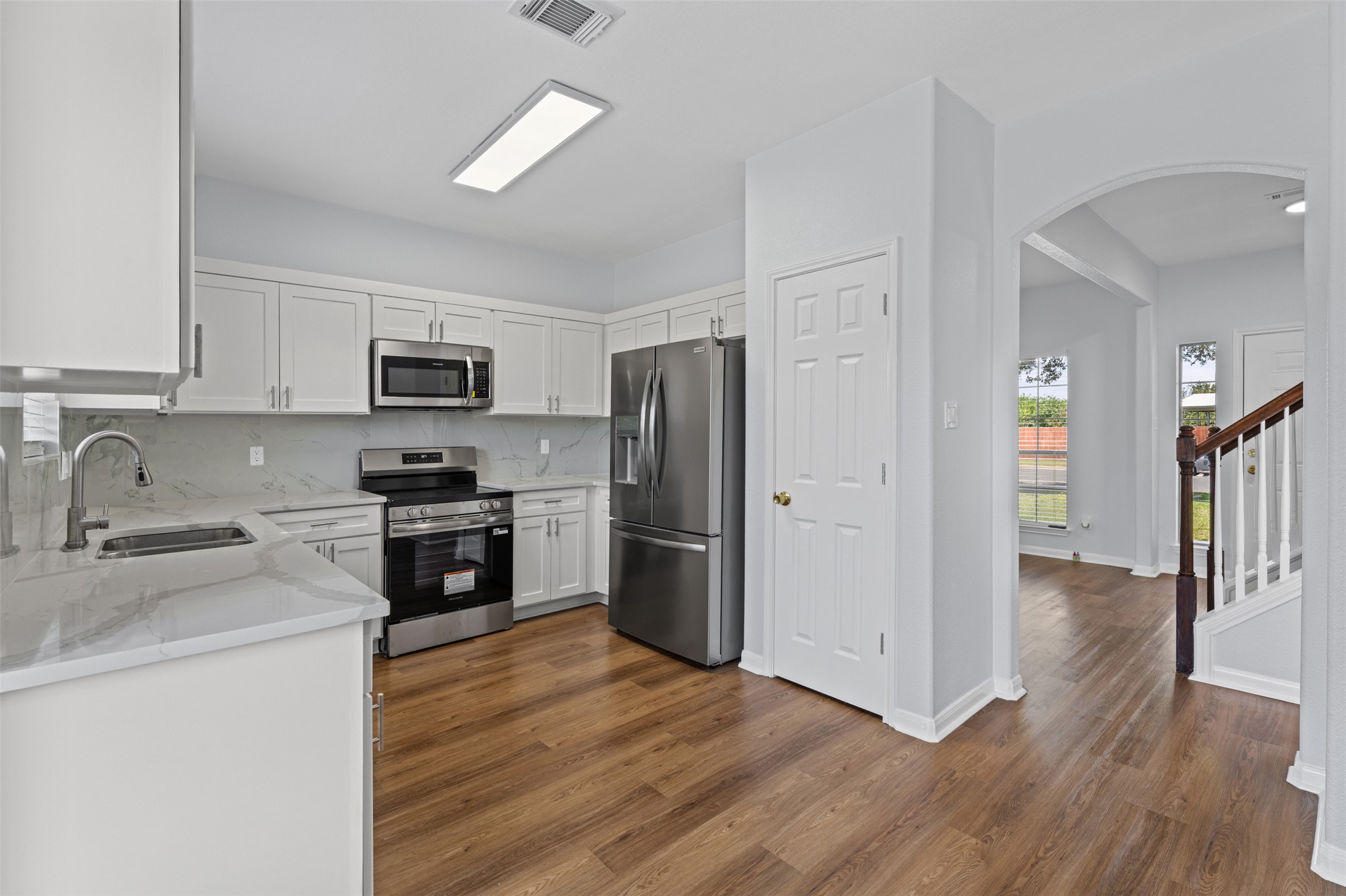 243 Engineers Pass Jarrell, TX 76537 - Photo 8 of 40 Kitchen featuring white cabinetry, stainless steel appliances, marble-look countertops, and wood-finish flooring