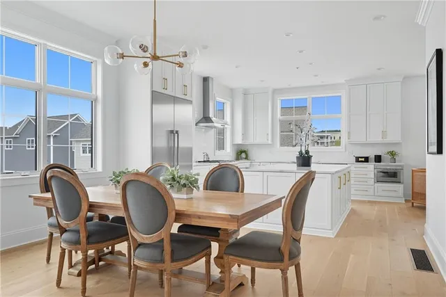a living room with stainless steel appliances furniture a chandelier and a wooden floor