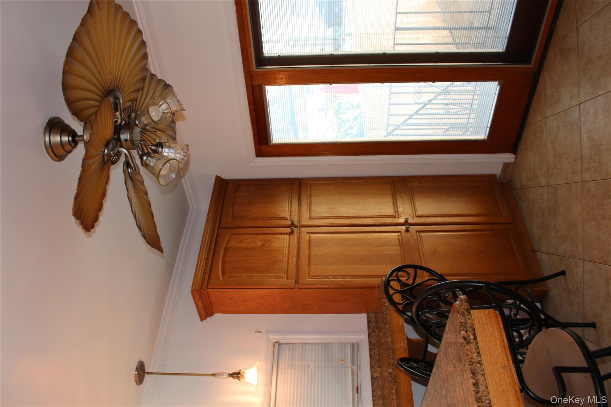 2973 Harding Avenue Bronx, NY 10465 - Photo 11 of 27 Kitchen with brown cabinets, crown molding, ceiling fan, light tile patterned floors, and dark countertops