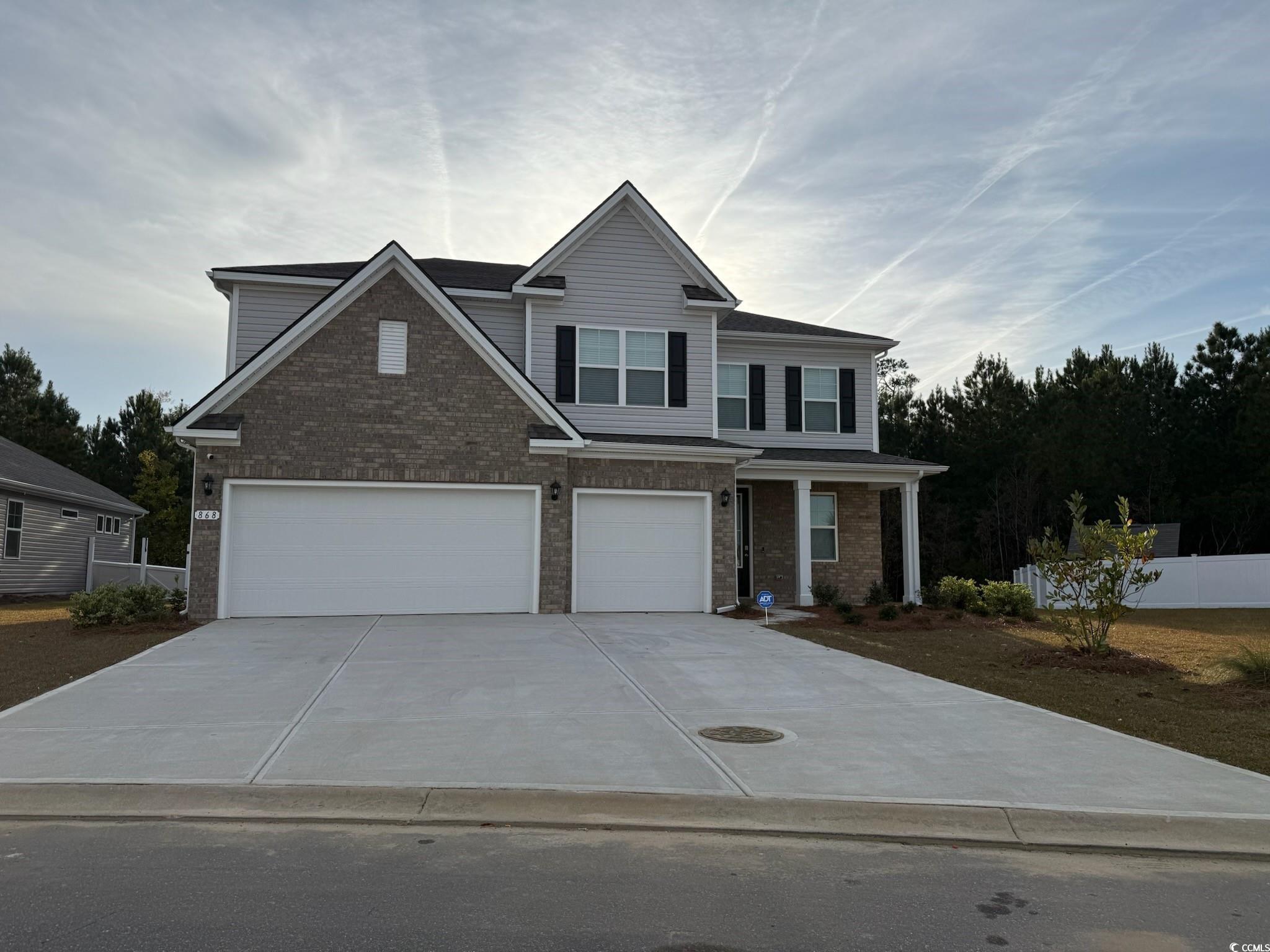 View of front of house featuring concrete driveway, a porch, brick siding, and a garage
