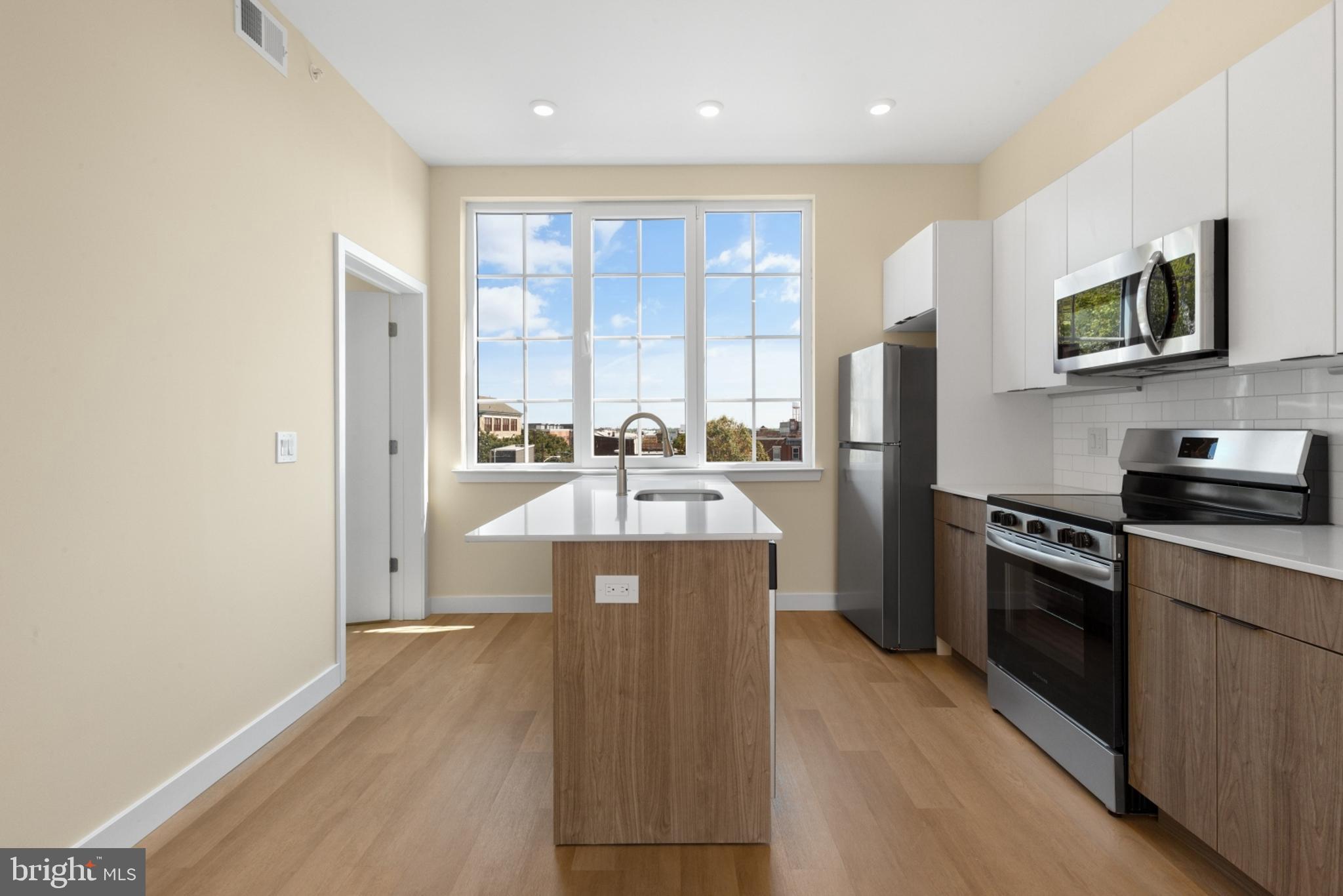 a kitchen with stainless steel appliances granite countertop a refrigerator a stove top oven a sink and dishwasher