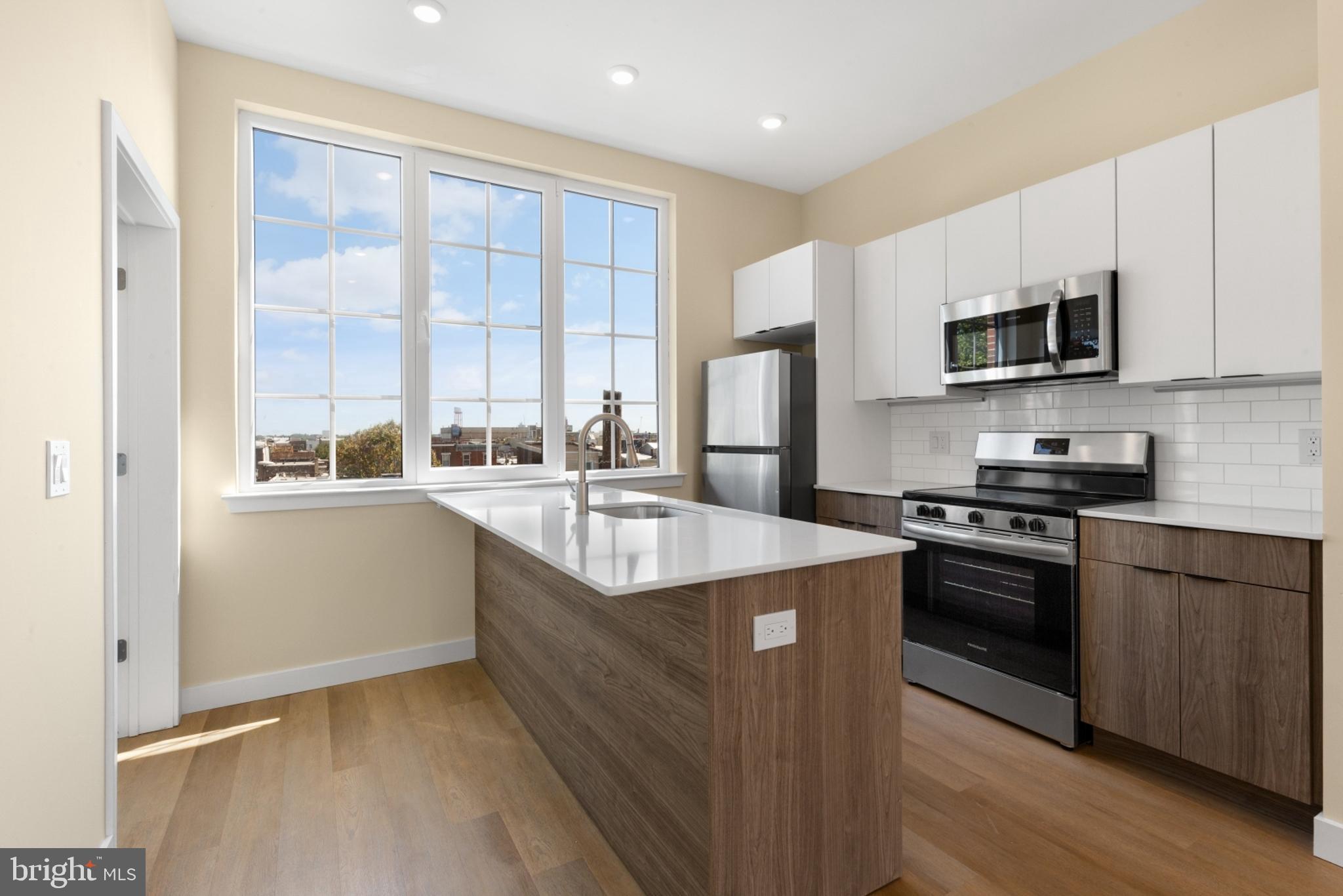 1701 South 4th Street, Unit 407 Philadelphia, PA 19148 - Photo 12 of 31 a kitchen with stainless steel appliances granite countertop a stove a sink and a refrigerator