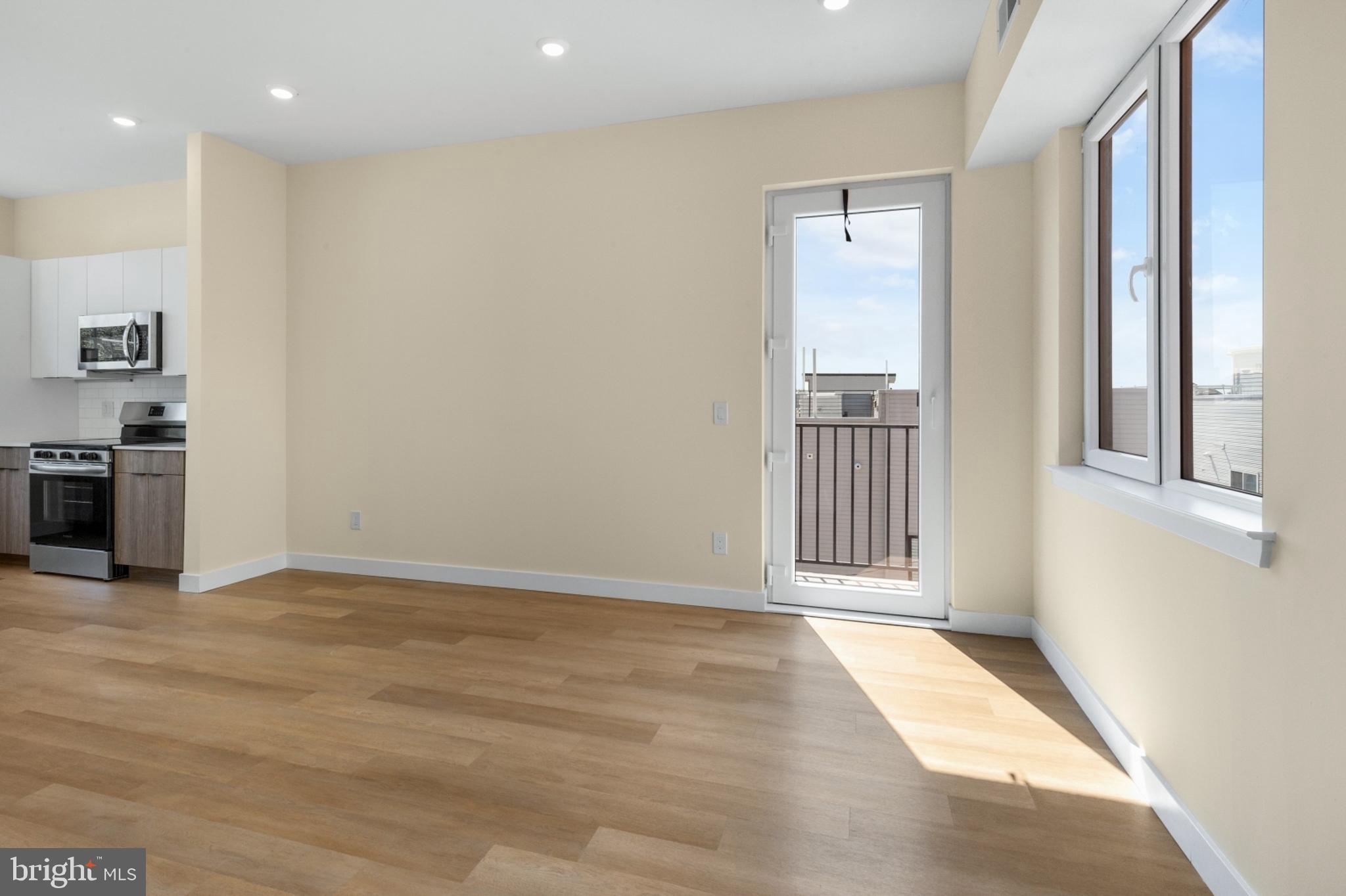 1701 South 4th Street, Unit 407 Philadelphia, PA 19148 - Photo 6 of 31 a view of a hallway with wooden floor and a kitchen