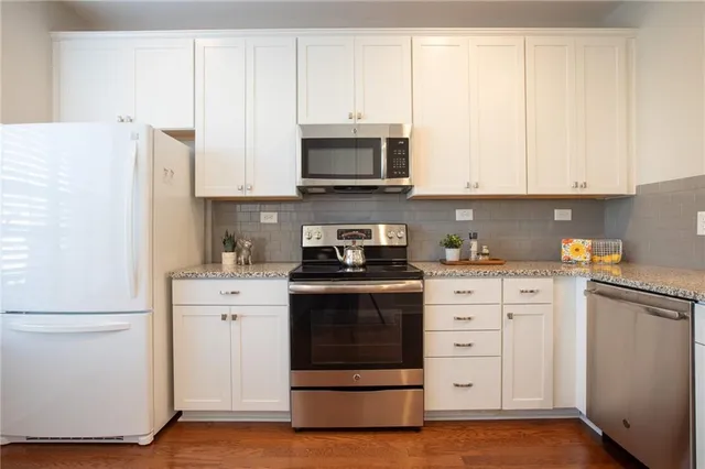 a kitchen with stainless steel appliances granite countertop a refrigerator stove and white cabinets