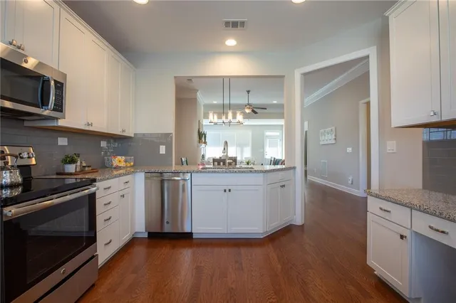 a kitchen with stainless steel appliances granite countertop a stove a sink and white cabinets