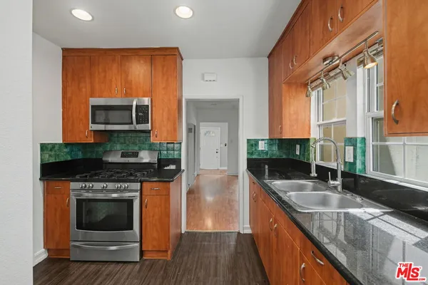 a kitchen with granite countertop a stove a sink and a microwave