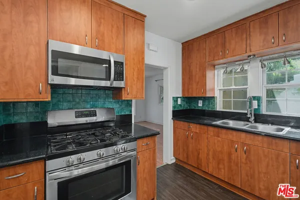 a kitchen with granite countertop stainless steel appliances a stove microwave and sink