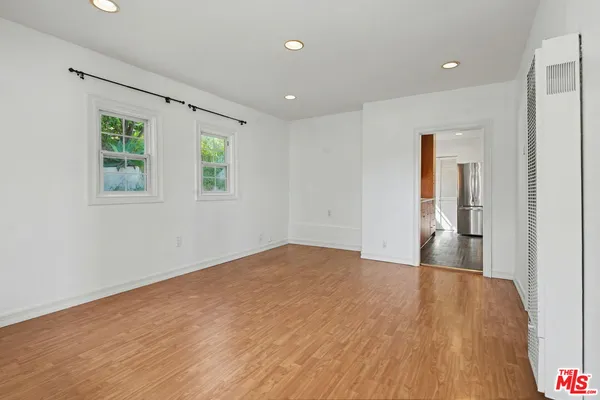 a view of an empty room with wooden floor and a window