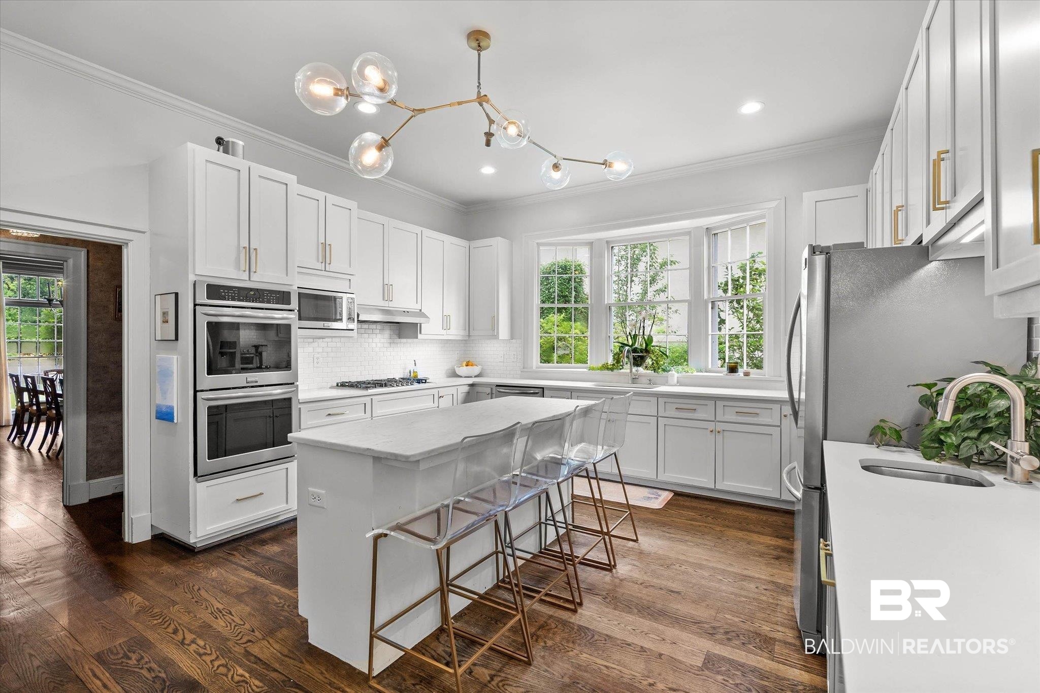 3908 Yester Place Mobile, AL 36608 - Photo 16 of 45 Bright kitchen featuring white cabinetry, a central island, stainless steel appliances, a bay window, and wood-finish flooring