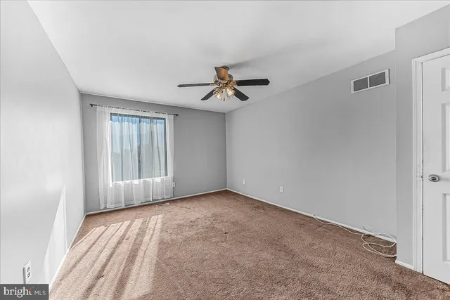 an empty room with a window and a fan