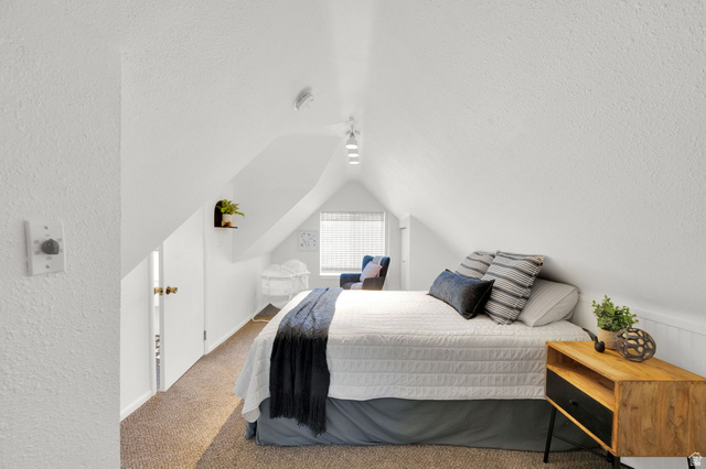 446 South 300 East Provo, UT 84606 - Photo 26 of 32 Sloped ceilings define this space, featuring carpet flooring, track lighting, a window with blinds, and a built-in wall shelf