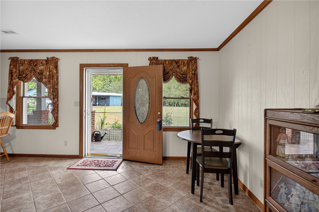 145 State Rd S-4-935 Pendleton, SC 29670 - Photo 10 of 47 The inviting entryway features a sturdy wood door and tiled flooring, welcoming guests with rustic charm.