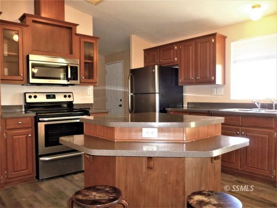 770 Alpine Way Ridgecrest, CA 93555 - Photo 17 of 50 a kitchen with a stove a microwave and wooden cabinets