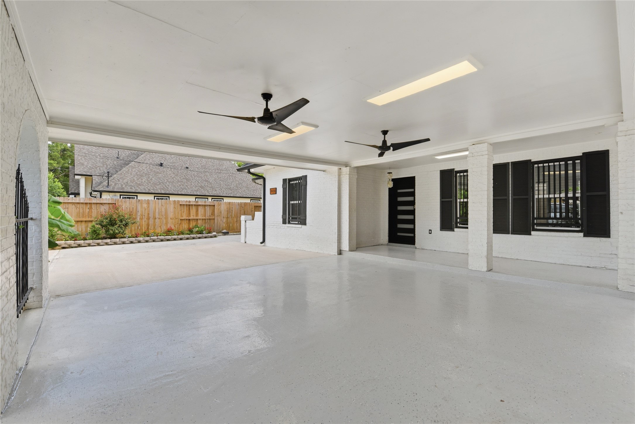 9403 Spaulding Street Houston, TX 77016 - Photo 4 of 50 This is a spacious covered patio with a sleek modern design, featuring ceiling fans, ample lighting, and a view of a landscaped backyard. It's perfect for outdoor relaxation and entertaining.