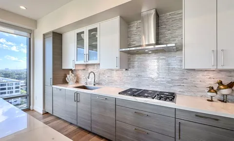 a kitchen with granite countertop a stove a sink and white cabinets