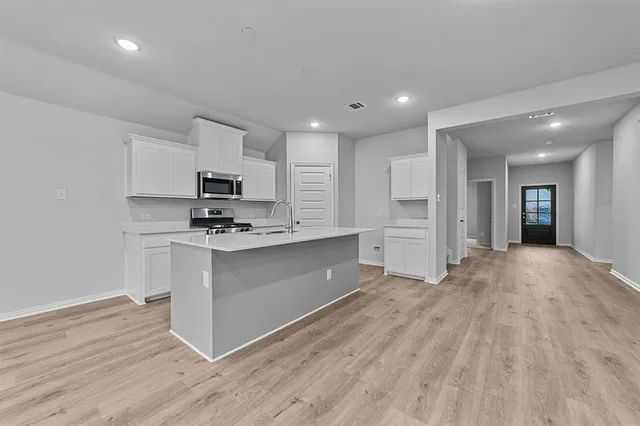 a kitchen with granite countertop a stove a sink and a refrigerator