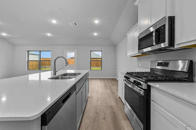 a kitchen with stainless steel appliances granite countertop a stove a sink and a microwave