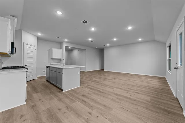 a open kitchen with kitchen island a sink dishwasher stove with wooden floors