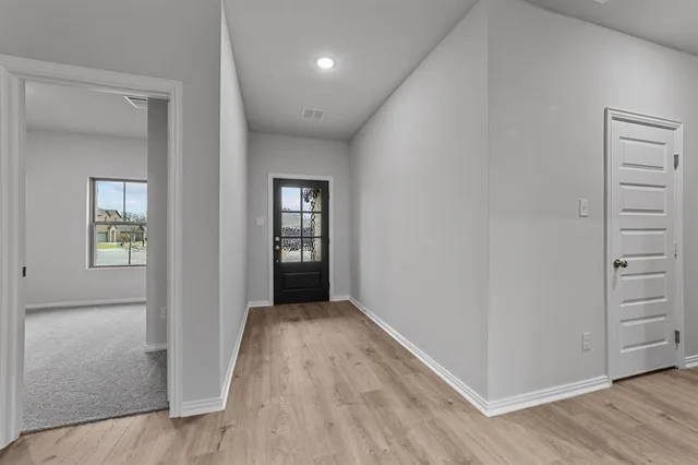an empty room with wooden floor closet and windows