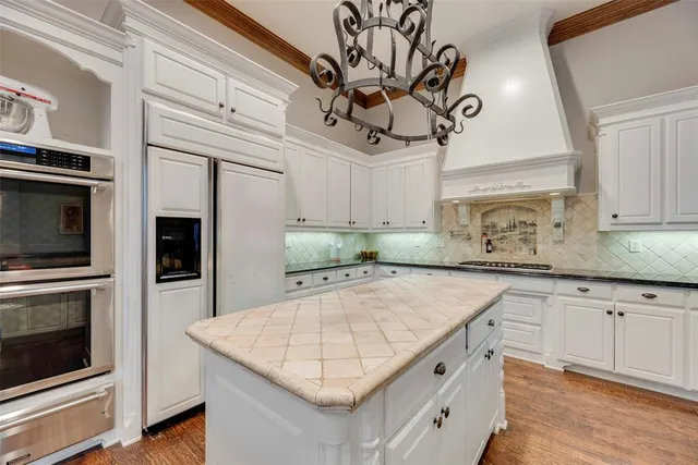 a kitchen with stainless steel appliances granite countertop a sink a microwave oven a stove and white cabinets