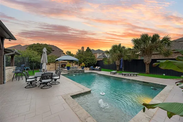 a view of a swimming pool with lawn chairs and a dining table under an umbrella