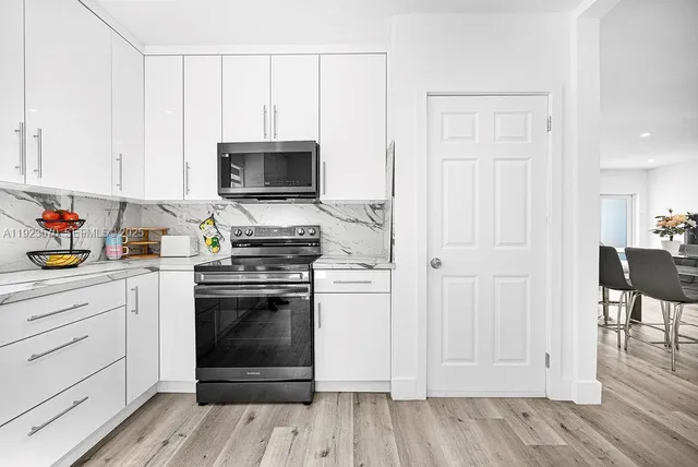 a kitchen with stainless steel appliances granite countertop a stove and white cabinets