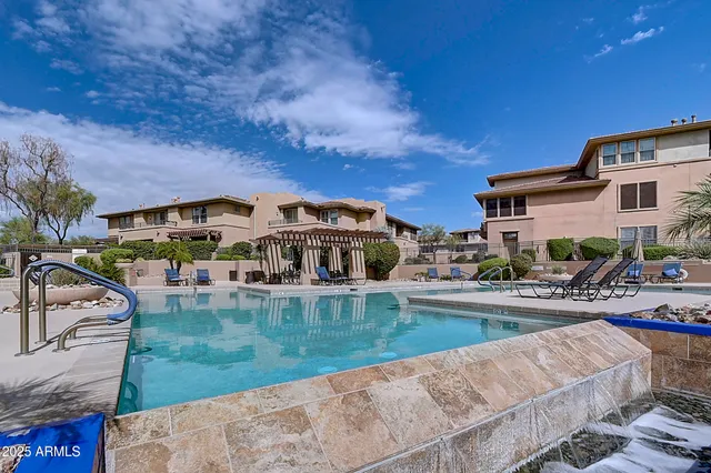 a view of a patio with a table and chairs under an umbrella with a barbeque