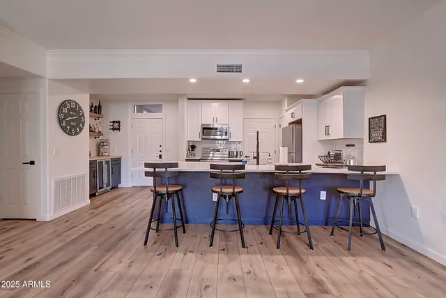 a kitchen with stainless steel appliances a table chairs refrigerator and microwave