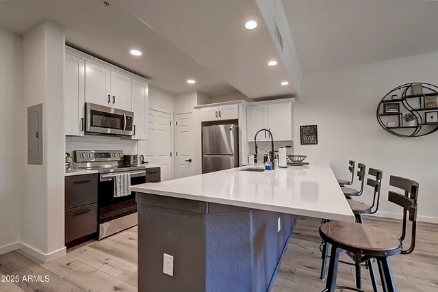 a living room with stainless steel appliances kitchen island a table and chairs in it