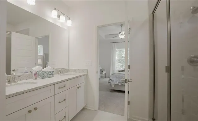 a en suite bathroom with a granite countertop double vanity sink and mirror