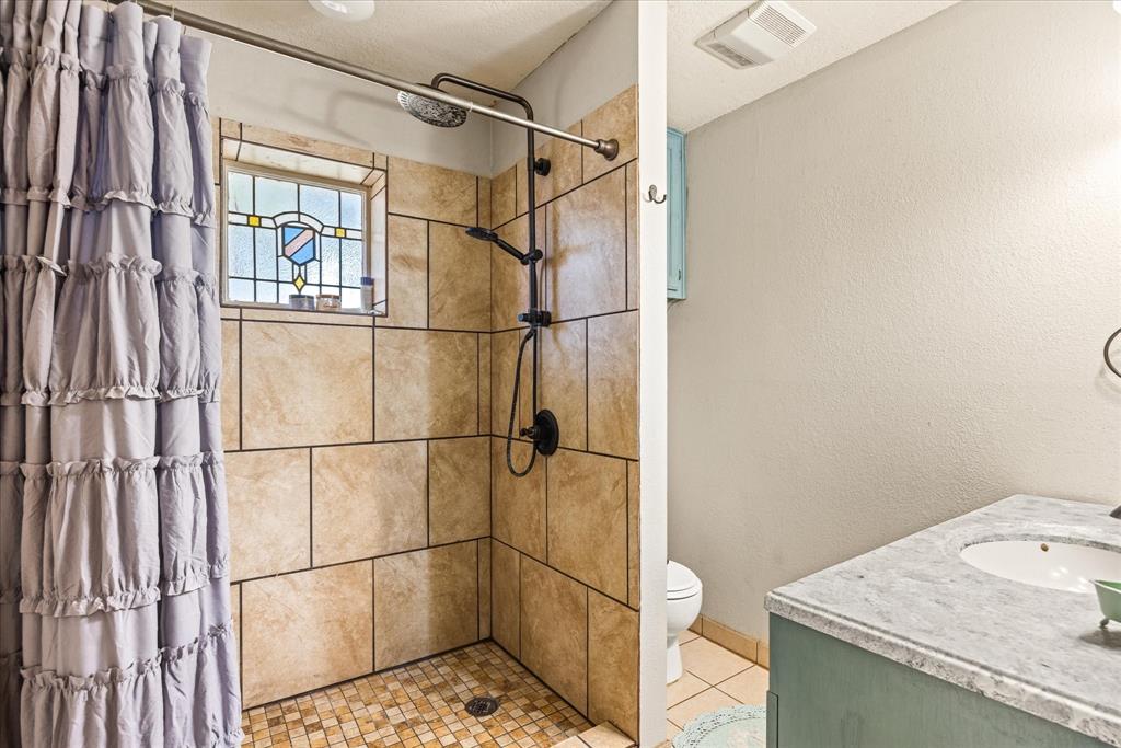 614 Overhill Road Granbury, TX 76048 - Photo 16 of 40 a bathroom with a granite countertop sink and a shower