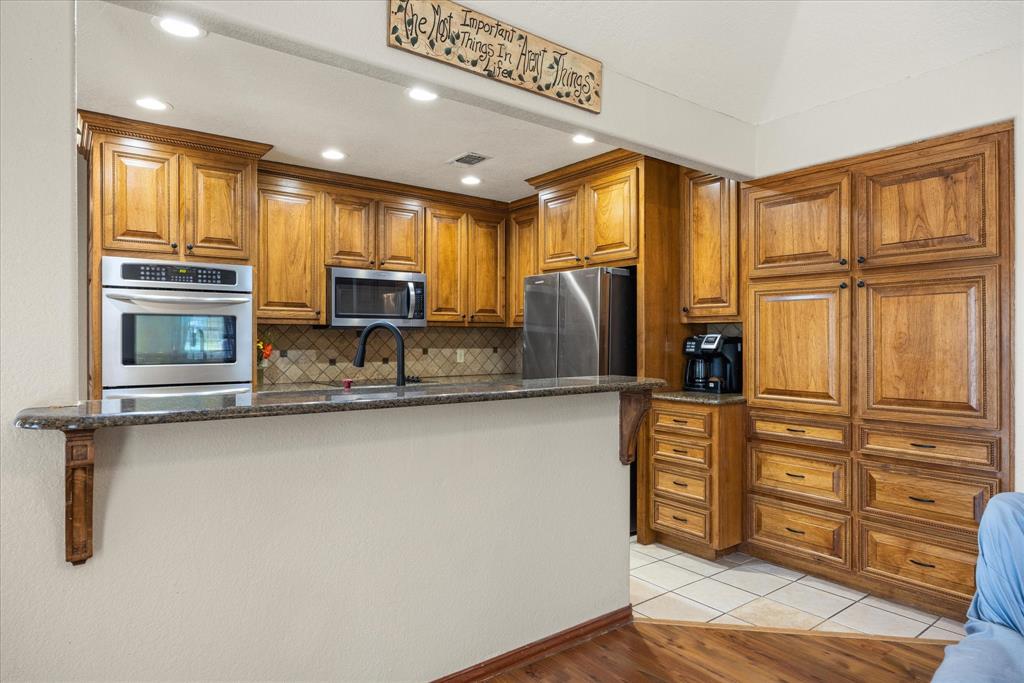 614 Overhill Road Granbury, TX 76048 - Photo 18 of 40 a kitchen with stainless steel appliances granite countertop a refrigerator a stove and a sink with wooden floor