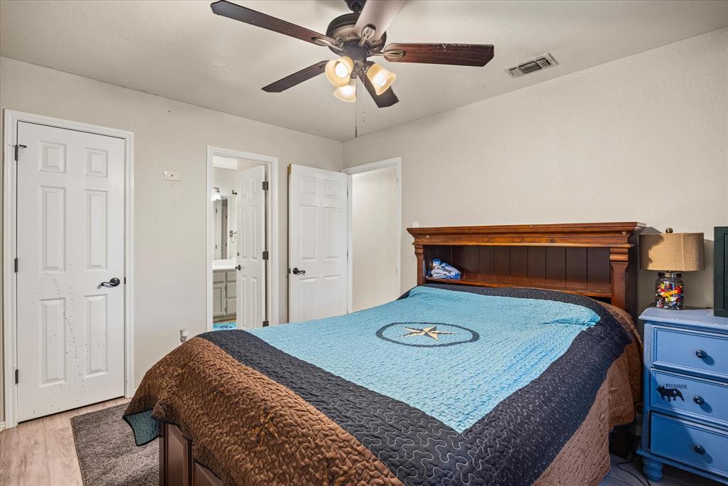 614 Overhill Road Granbury, TX 76048 - Photo 24 of 40 a bedroom with a bed and a chandelier