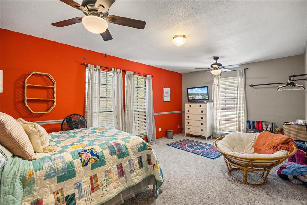 614 Overhill Road Granbury, TX 76048 - Photo 27 of 40 a bedroom with a bed and a chandelier