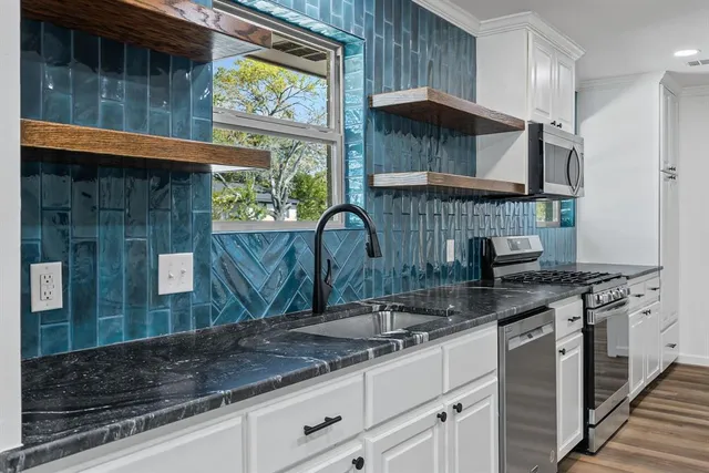 a kitchen with stainless steel appliances granite countertop a sink a stove and a wooden cabinets