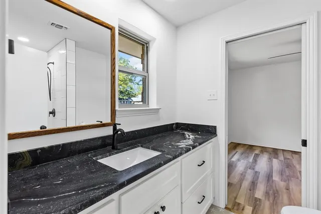 a bathroom with a granite countertop sink and a mirror