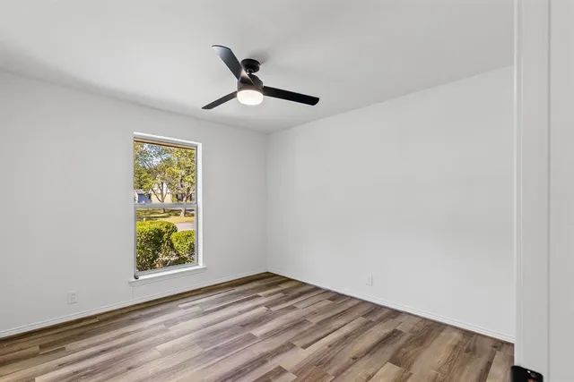 a view of empty room with window and wooden floor