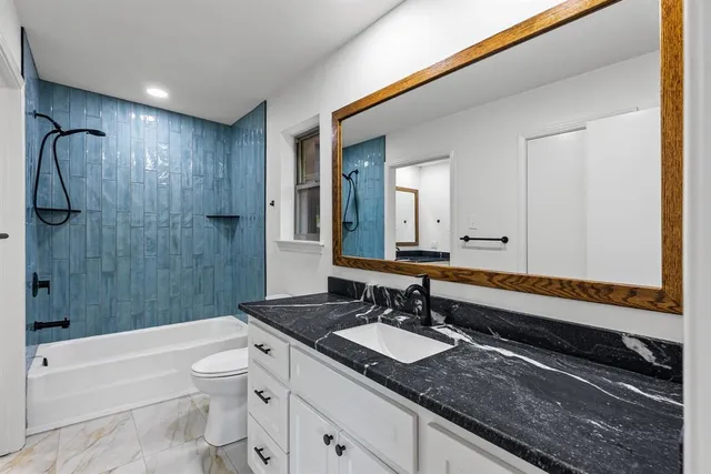 a bathroom with a granite countertop sink toilet and shower