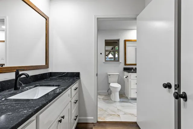 a bathroom with a granite countertop sink toilet and mirror