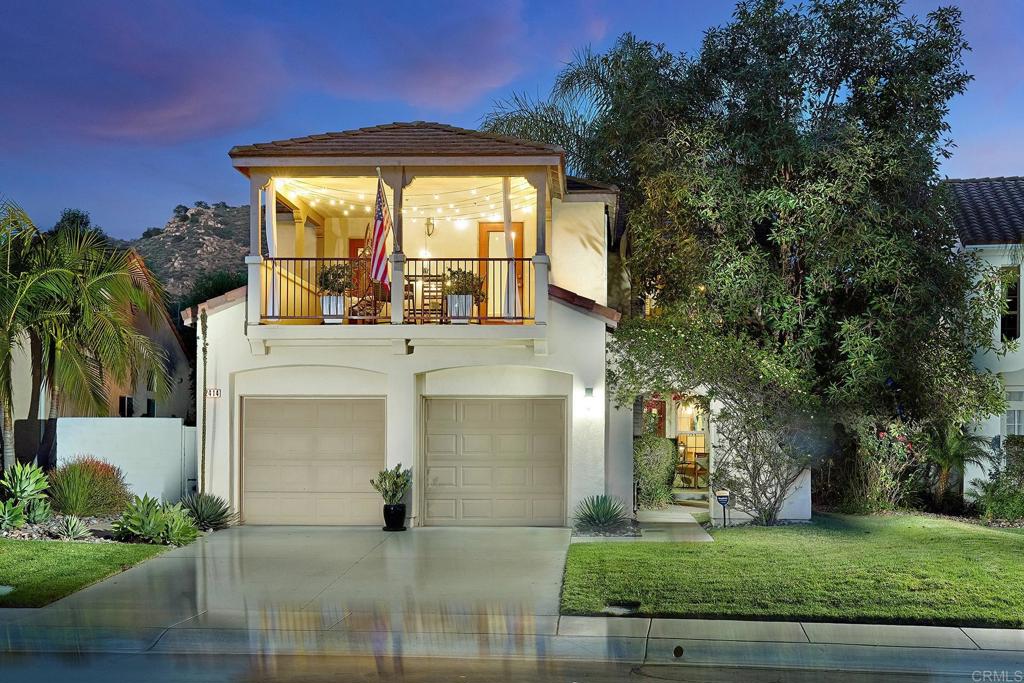a view of a white house with a large windows and a yard with plants and large trees