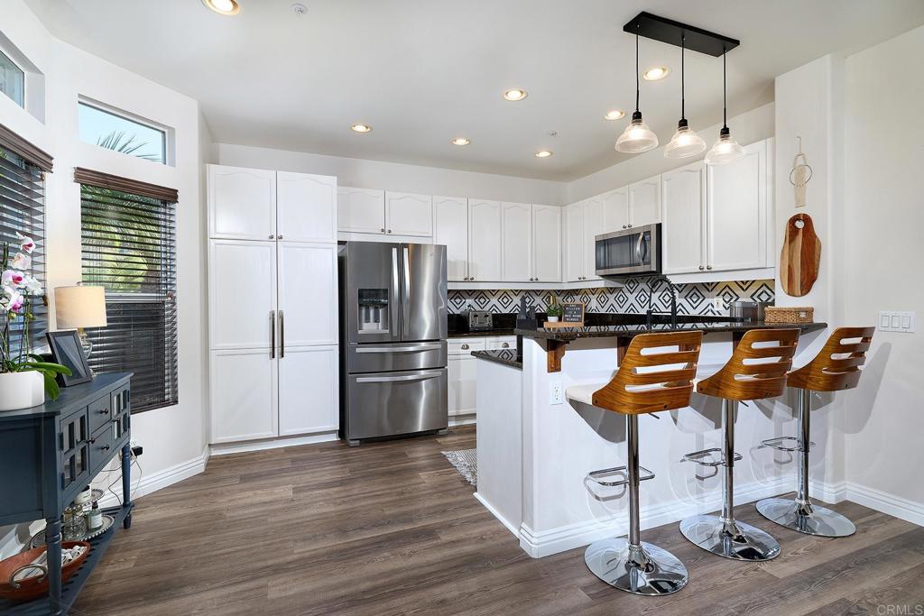 2414 Fallbrook Place Escondido, CA 92027 - Photo 33 of 63 a kitchen with stainless steel appliances granite countertop a refrigerator a stove a sink dishwasher a dining table and chairs with wooden floor