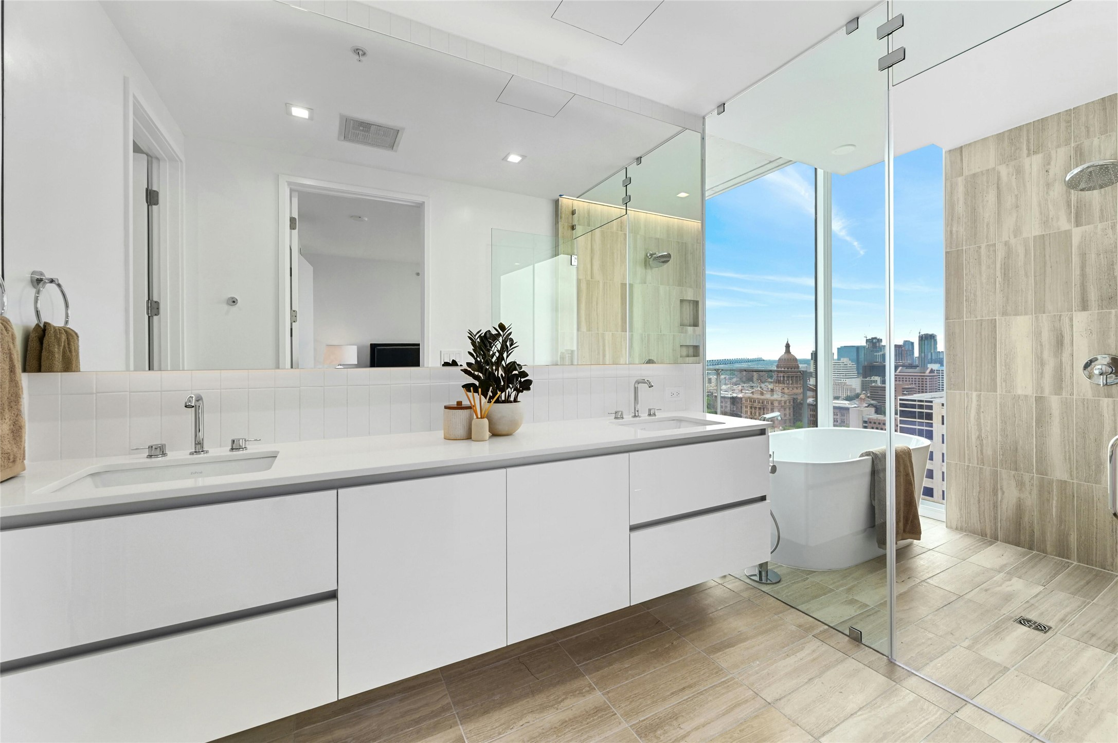 313 West 17th Street, Unit 1807 Austin, TX 78701 - Photo 7 of 39 The primary bathroom boasts a dual vanity with cabinets, a frameless glass shower, and a bathtub. Enjoy the city view while soaking in the bathtub, surrounded by floor-to-ceiling windows that fill the space with natural light and offer a stunning urban backdrop.