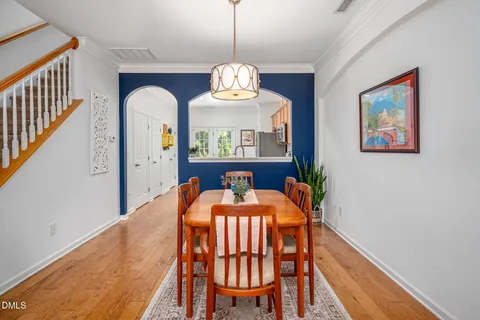 a dining room with wooden floor a chandelier a wooden table and chairs