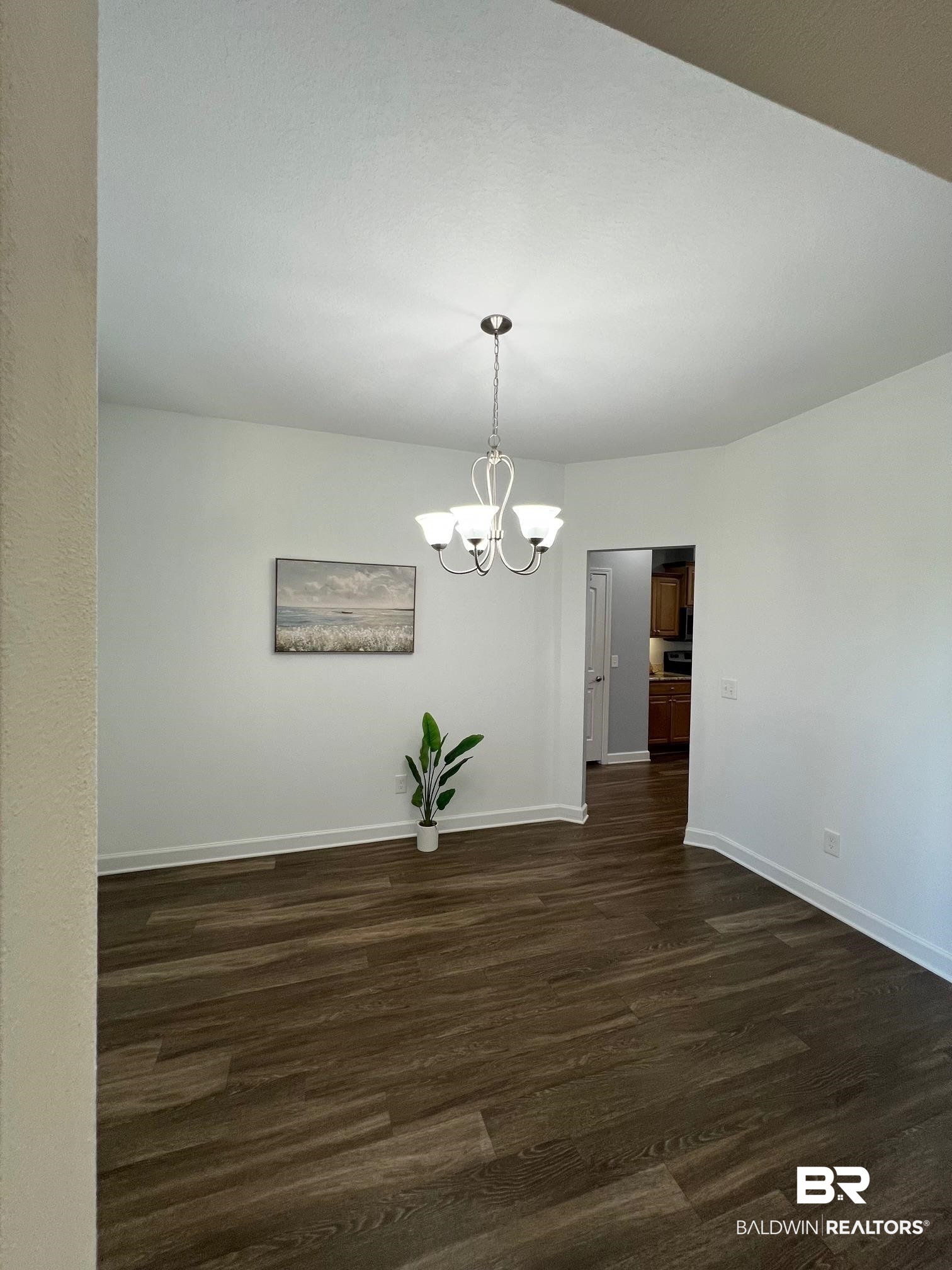 10257 Lyttleton Loop Lillian, AL 36549 - Photo 13 of 31 Unfurnished dining area with dark wood finished floors and a chandelier