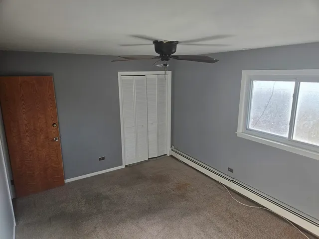 an empty room with windows and fan